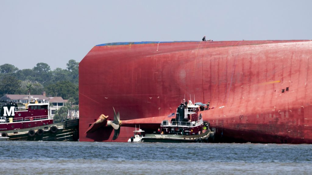 Rescuers work Monday near the stern of the vessel Golden Ray as it lays on its side near the Moran tugboat Dorothy Moran in Jekyll Island. Coast Guard rescuers have made contact with four South Korean crew members trapped inside the massive cargo ship off the coast of Georgia. (Stephen B. Morton/Associated Press)