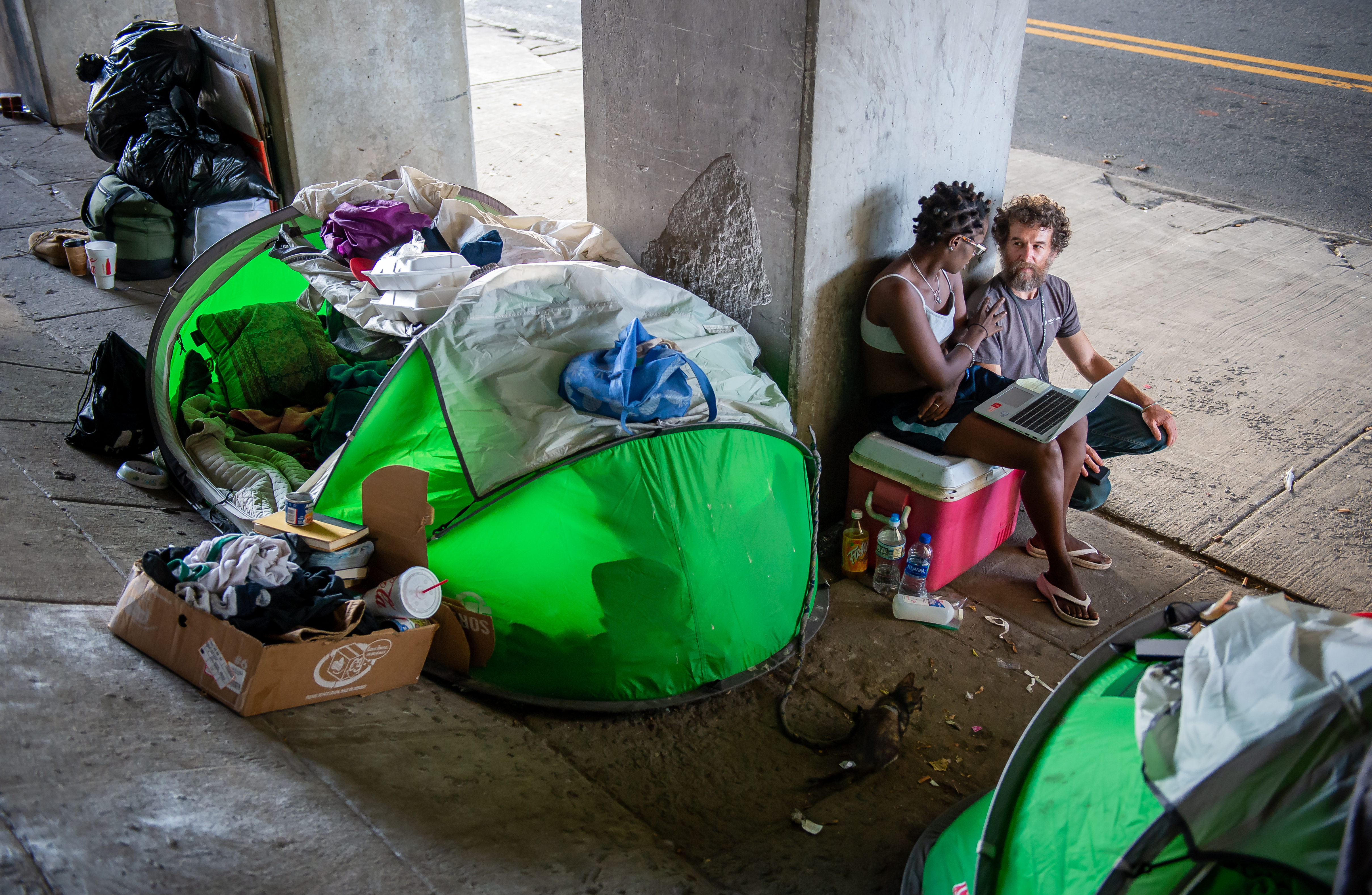 Social worker Matthew Reed (right) sits with Sopain Lawson under an I-20 bridge in downtown Atlanta, where Lawson is currently living in a homeless encampment on Monday, Sept. 9, 2019. 