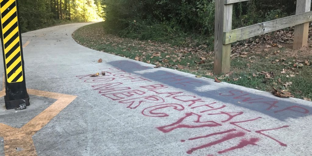 A message opposing the proposed land swap is spray painted on the walking trail at Intrenchment Creek Park. 