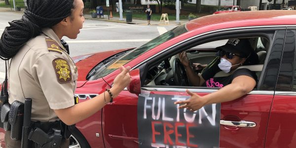 Mary Hooks, with Southers on New Ground, argues with a Fulton County Sheriff's Deputy blocking the road in Atlanta. Activist groups demanded the release of Fulton County Jail inmates Tuesday.