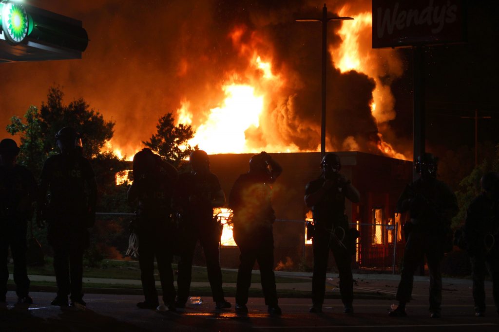 Atlanta police officers try to stop protesters from getting too close to the Wendy's as the building is completely engulfed in flames on Saturday. (Lily Oppenheimer) 
