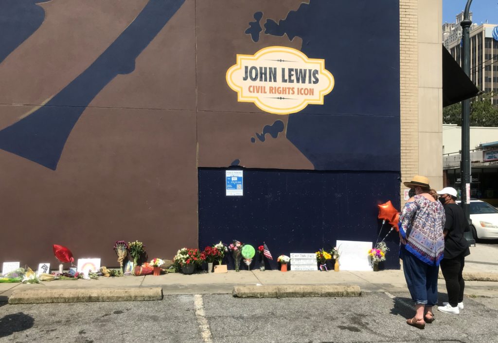 Mourners leave flowers near the John Lewis mural on Auburn Avenue. 