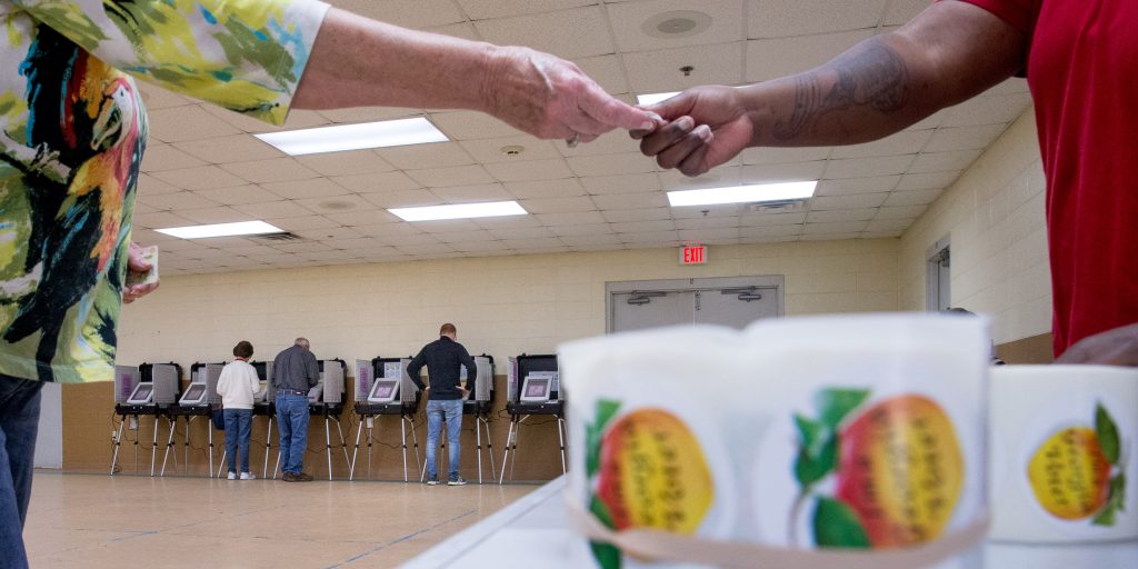 "I'm a Georgia Voter" stickers with peaches are handed out to residents as they vote during Georgia's primary election at their polling station at South Lowndes Recreation Complex in Lake Park, Ga., Tuesday, March 1, 2016. (AP Photo/Andrew Harnik)