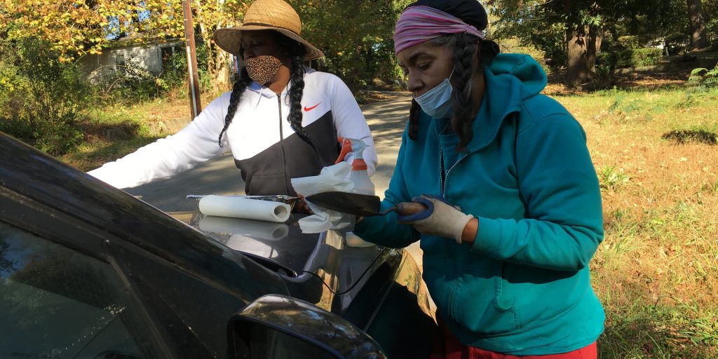 Natashia Jones, left, and Taranji Alvarado record information and clean their tools after taking soil samples for lead testing in Atlanta’s Grove Park neighborhood.