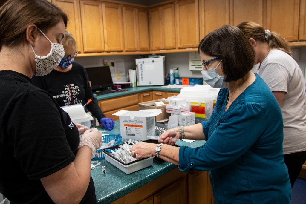 Dr. Jane Wilkov, in blue at right, prepares needles and doses of the Pfizer coronavirus vaccine Wednesday in Decatur. (Ron Harris/Associated Press)