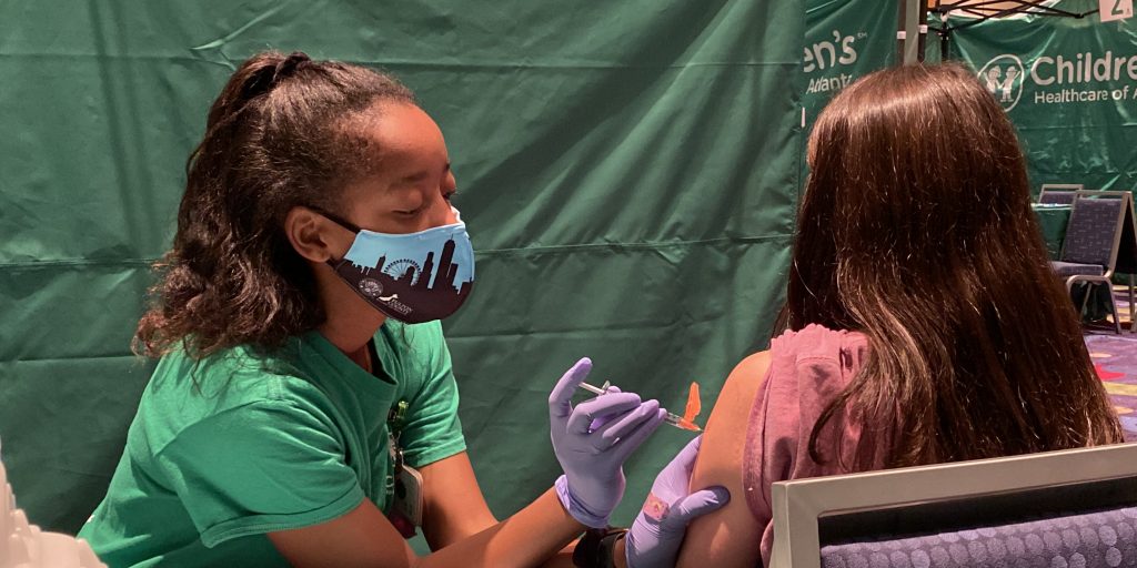 Tori Hood, an emergency room nurse at Children’s Healthcare of Atlanta, gives 15-year-old Tristan Linscott her first COVID-19 vaccine dose at a pop-up vaccination clinic at the Georgia International Convention Center in College Park.