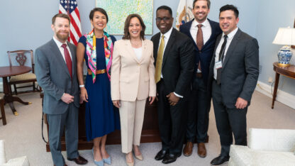 A group of people standing and smiling in the White House