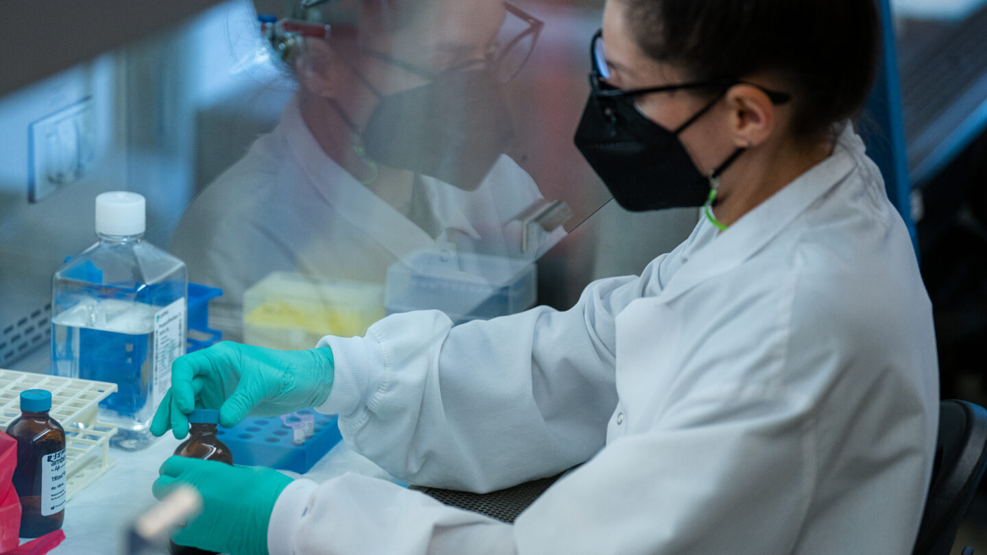 Ash Grimes works underneath a hood with a series of samples at the Hope Clinic Emory Vaccine Center's labortory as part of the research to develop a potential first-ever HIV vaccine. (Matthew Pearson/WABE