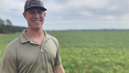 Georgia farmer Riley Davis stands in front of a field on his farm.