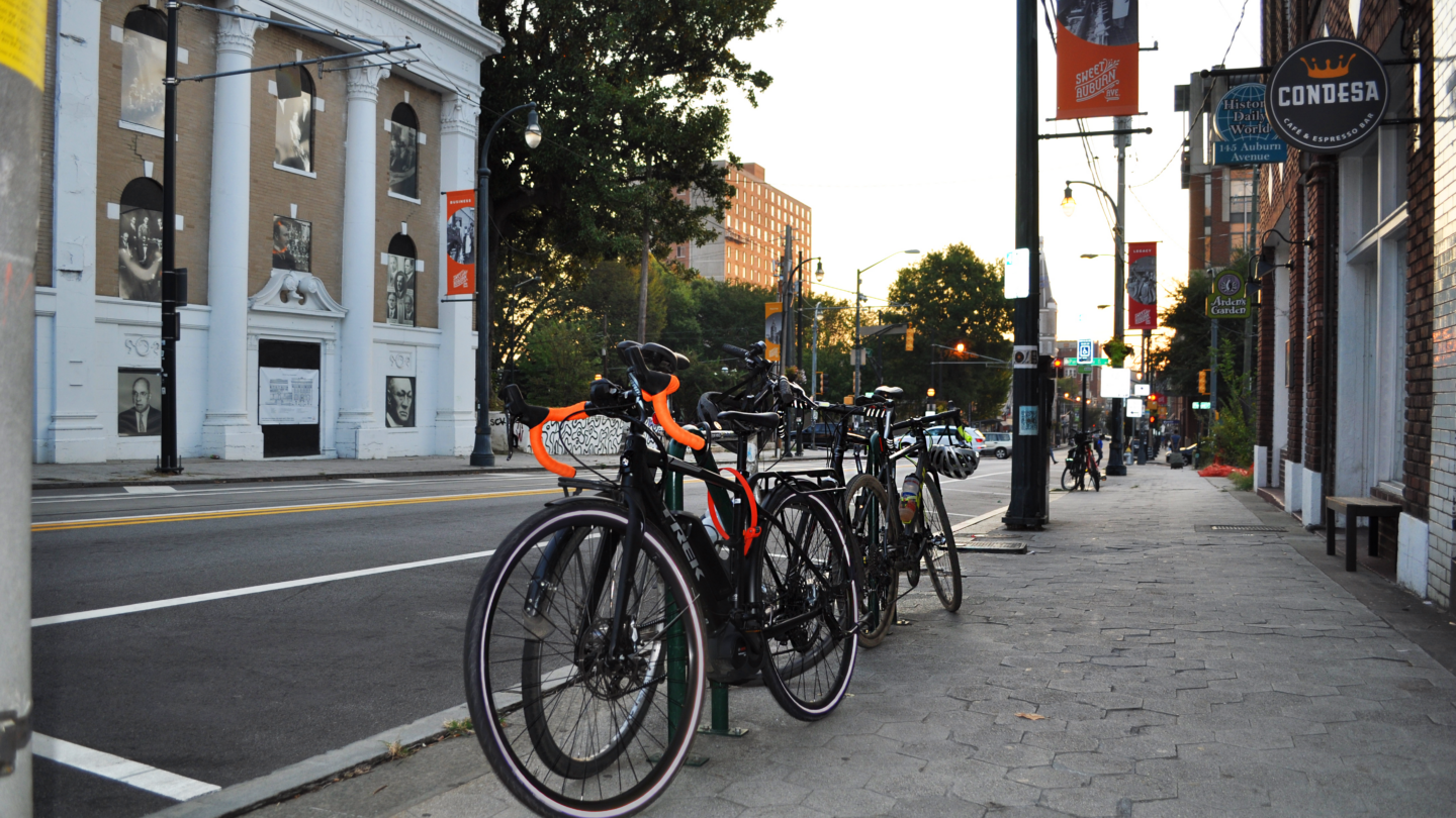 Several black bikes are locked to a bike rack along a city street in downtown Atlanta.