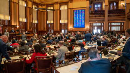 A group of people sitting in the Georgia House Chamber voting on a bill.