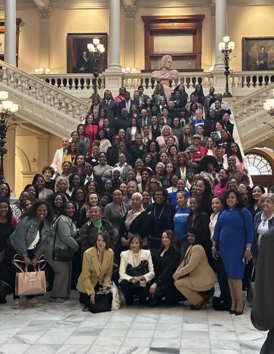 A group of people standing and smiling on top of stars in the State Capitol.