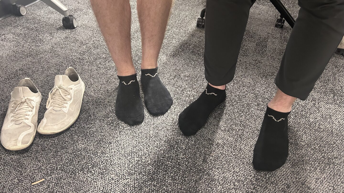 Two people standing next to each other wearing black socks.