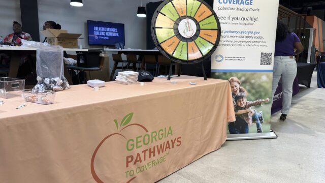 A long table with a tablecloth depicting the logo for Georgia Pathways to Coverage