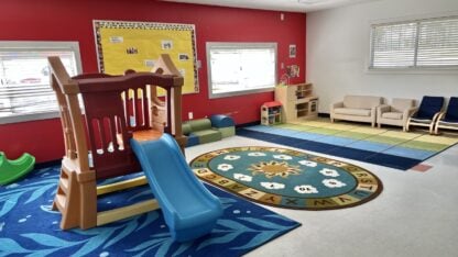 A classroom is shown with an indoor play area including a jungle gym