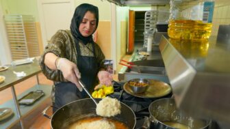 A woman ladles rice into a pot in a kitchen.