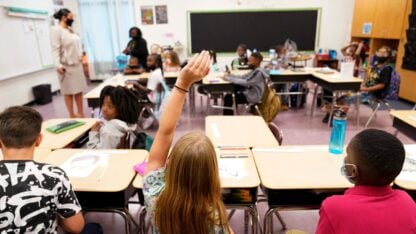 A child raises her hand in a classroom