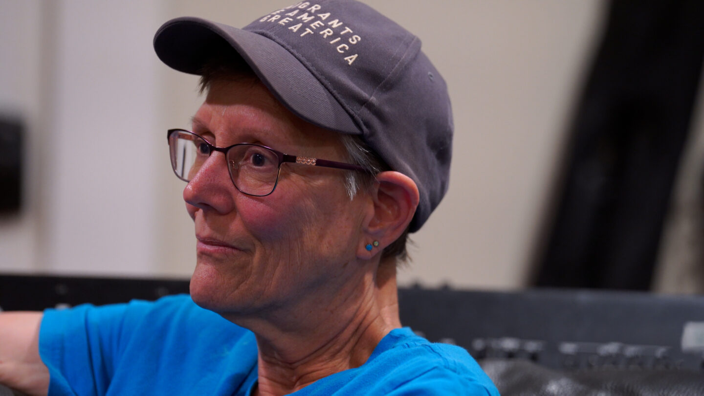 Elizabeth Dede wears glasses and a denim colored hat
