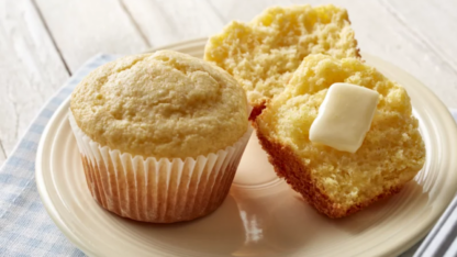 A photo of two Jiffy Cornbread muffins. One is split in half with butter.