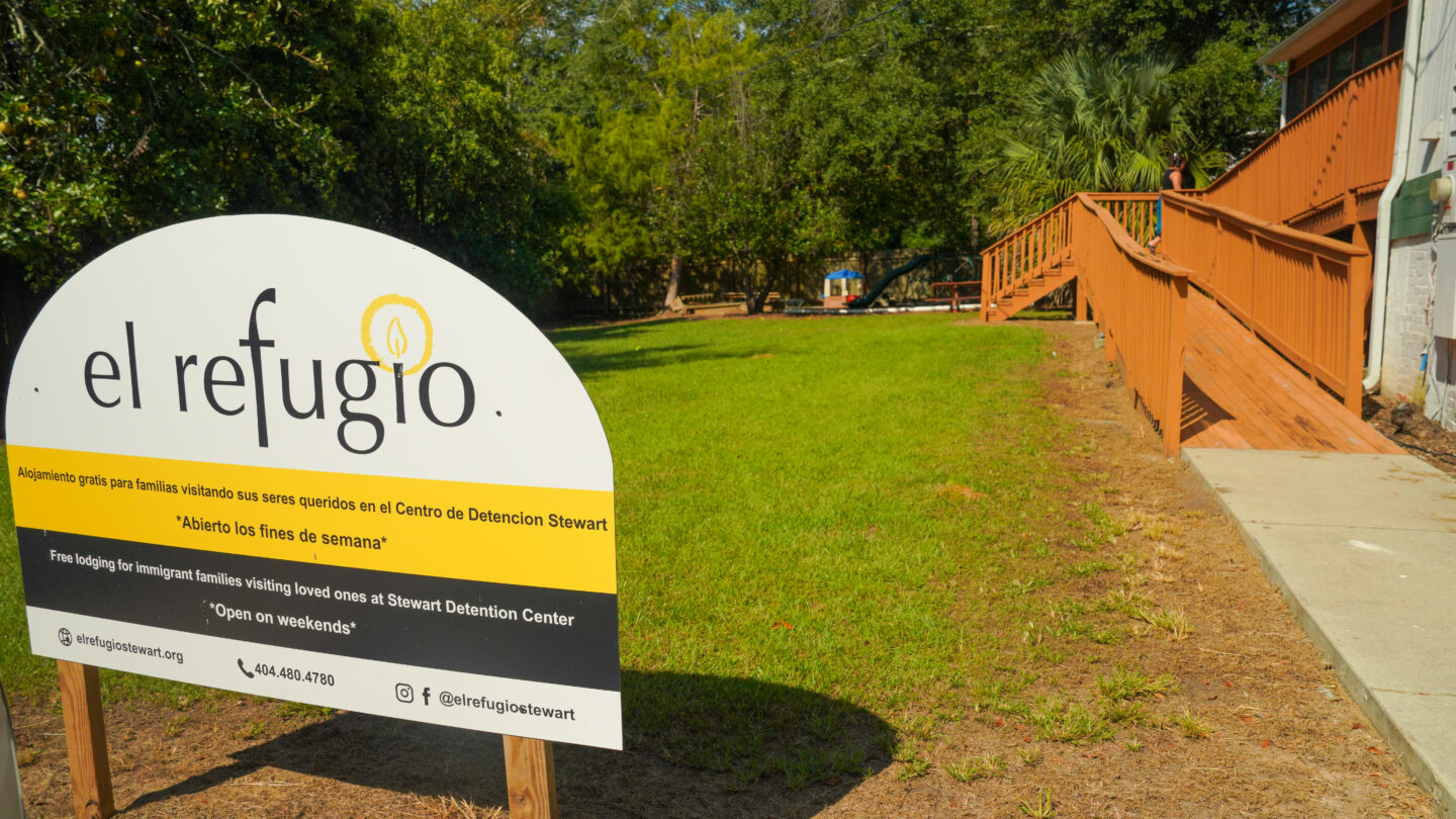 A white, half moon sign with a yellow and a black stripe that says el refugio