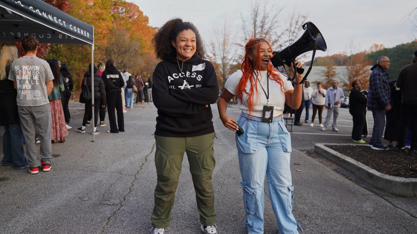 two women standing outside with a megaphone.