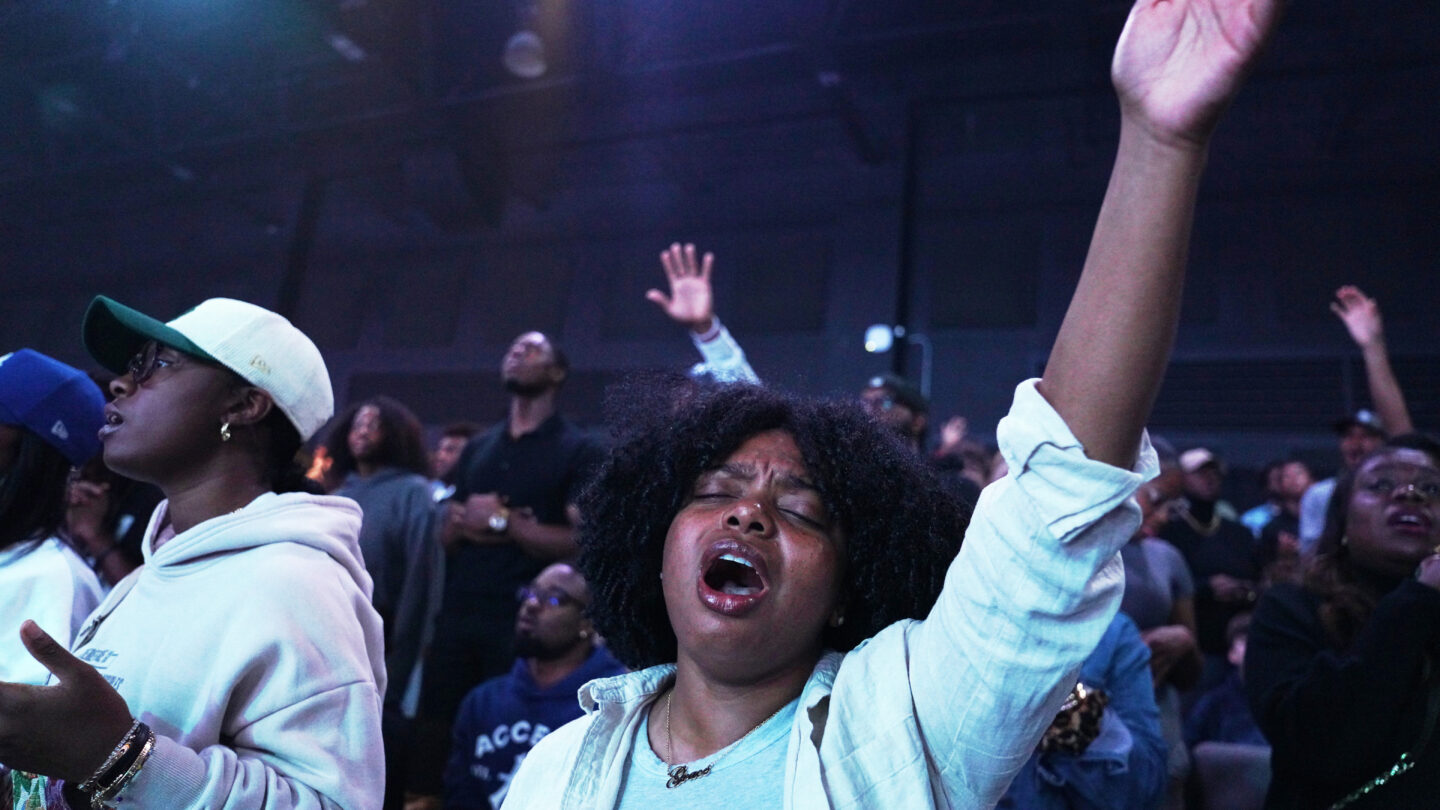 A woman lifts her up in praise.