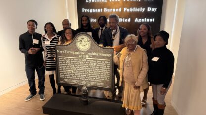 People stand behind a historical marker.