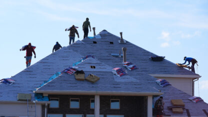 Workers on top of the roof of a house on a sunny day