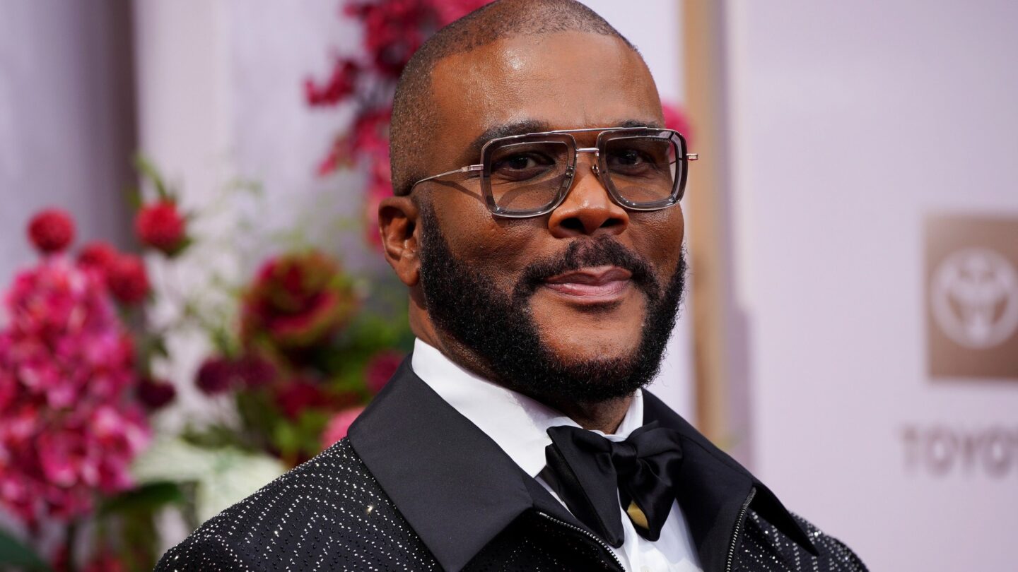 A man in a tuxedo and wearing sunglasses poses for pictures