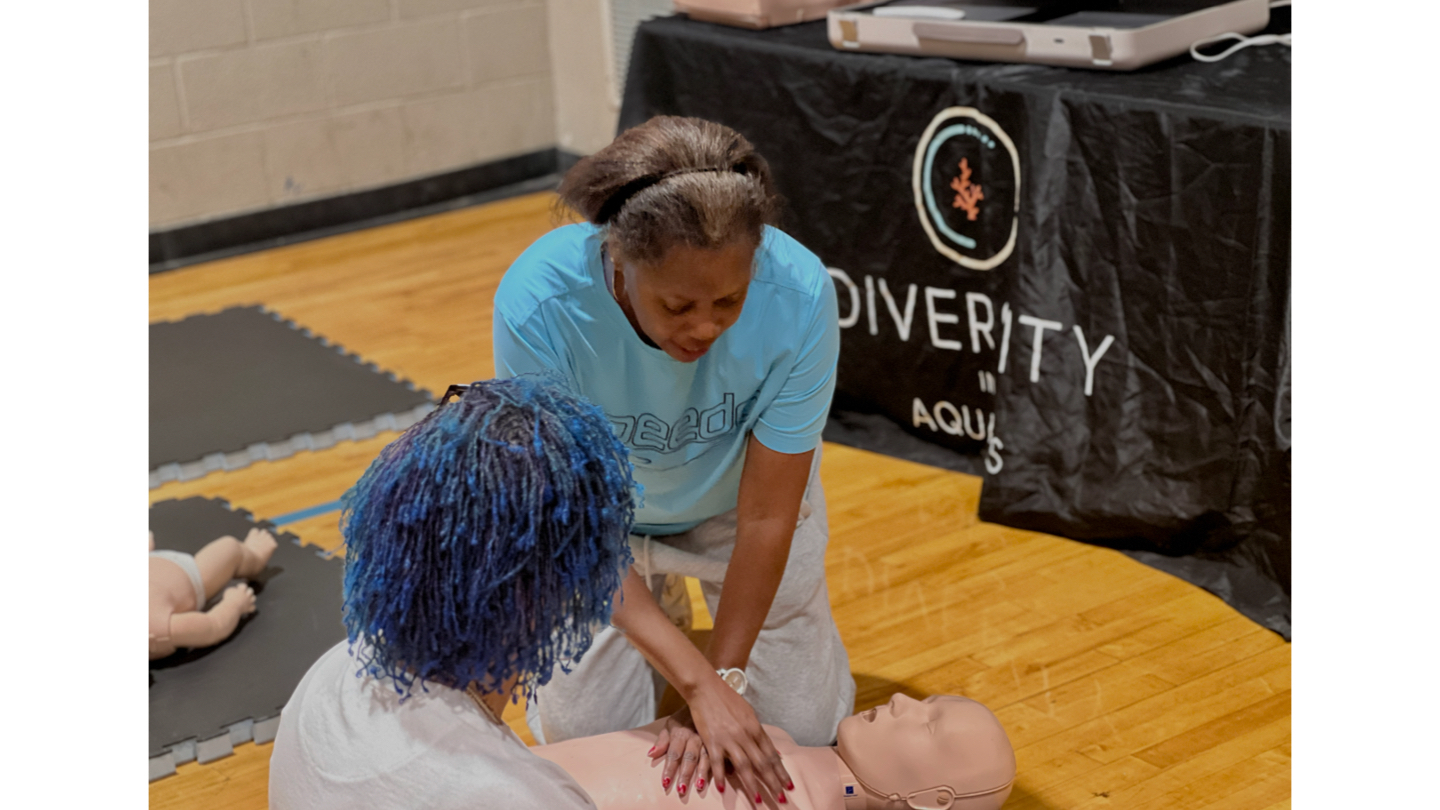 A staff member demonstrates CPR on a dummy