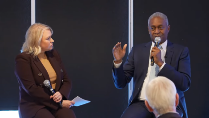 Raphael Bostic holds a microphone while talking to another person
