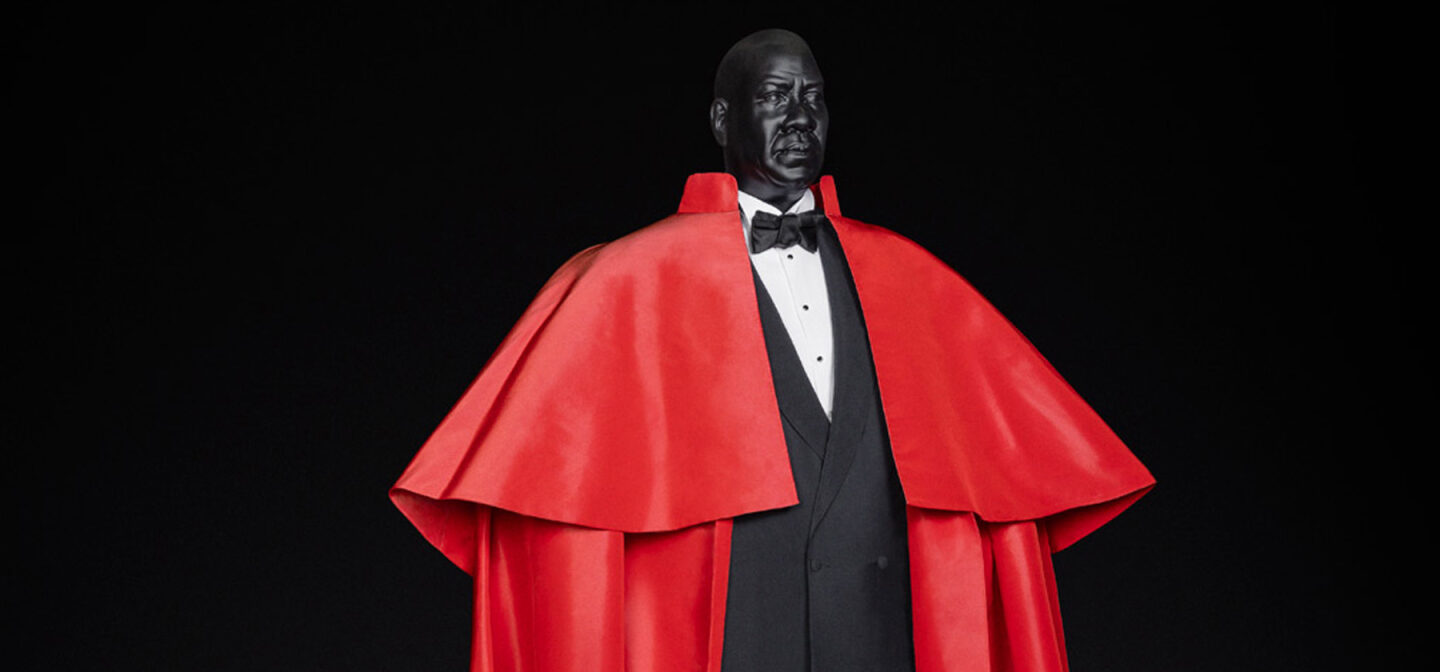 Custom mannequin modeled after Andre Leon Talley wearing a red cape and tuxedo