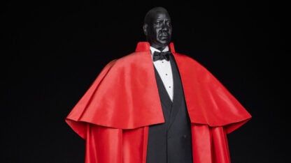 Custom mannequin modeled after Andre Leon Talley wearing a red cape and tuxedo