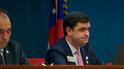Scott Hilton sits behind a desk at a committee hearing