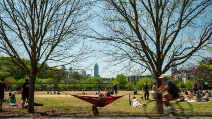 People gather on a lawn with the city skyline in the background
