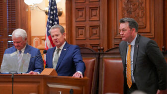 From left to right, House Speaker Jon Burns, Governor Brian Kemp, and Lieutenant Governor Burt Jones stand in front of the House chamber at the Georgia State Capitol