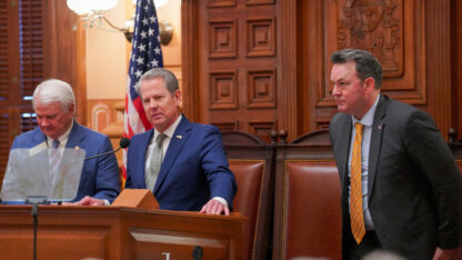 From left to right, House Speaker Jon Burns, Governor Brian Kemp, and Lieutenant Governor Burt Jones stand in front of the House chamber at the Georgia State Capitol