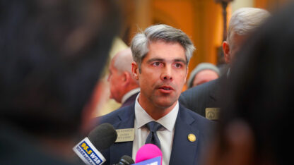 A lawmaker speaks into multiple microphones