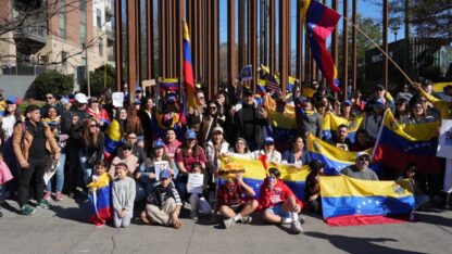 A group of people draped in Venezuelan flags pose for a photo at a rally on Atlanta's Beltline.