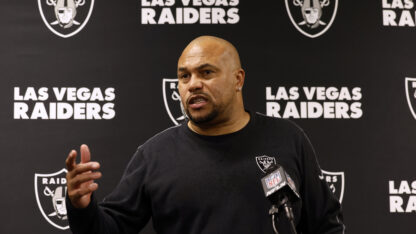 Antonio Pierce speaks at a press conference in front of a black Las Vegas Raiders