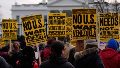 Yellow and black signs protesting the U.S. strikes in Venezuela Saturday are seen in front of the White House.