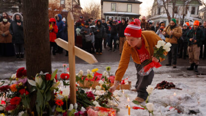 People lay flowers near a cross
