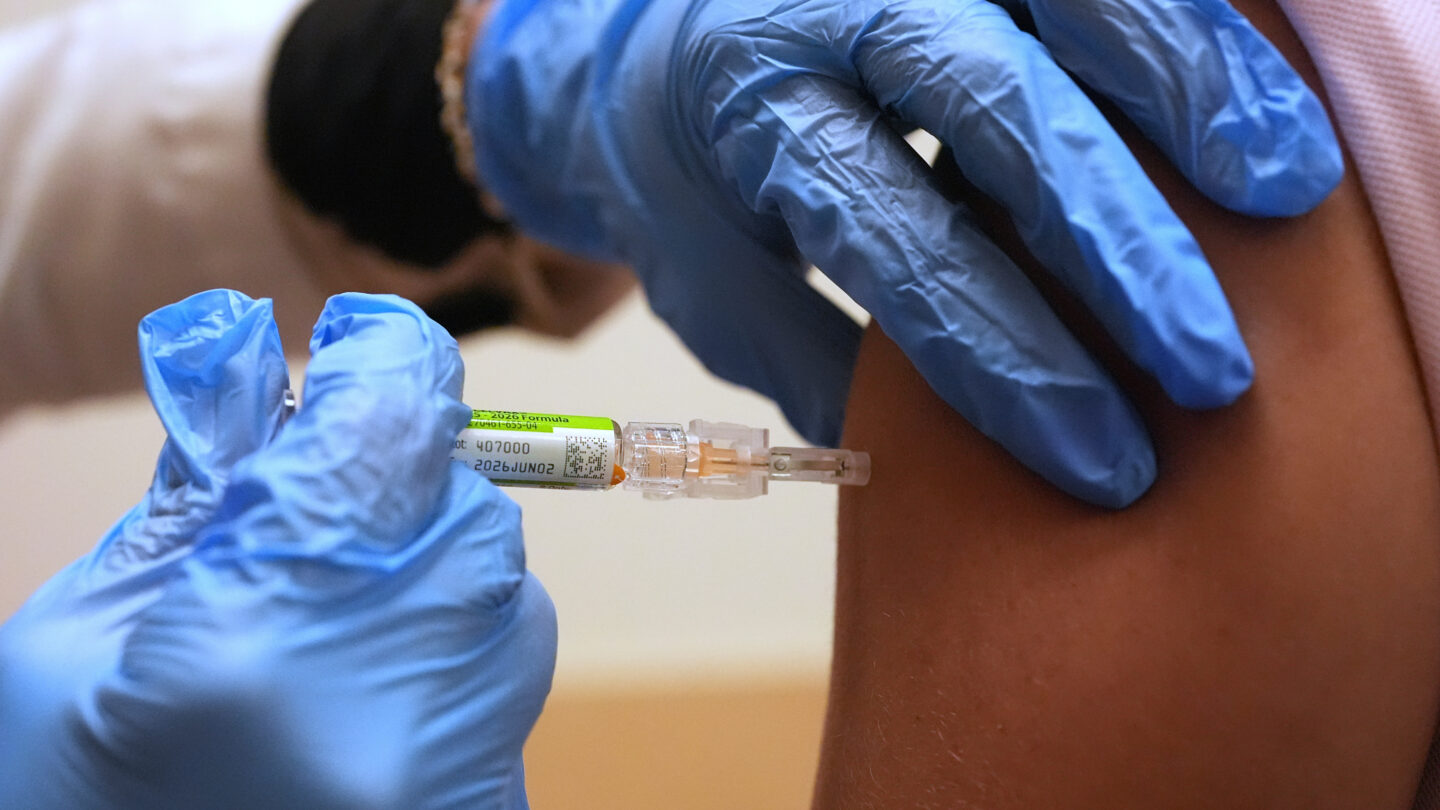 A professional in blue latex gloves administers a vaccine shot.