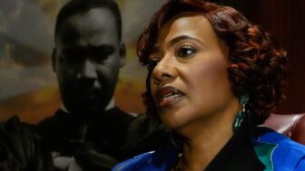 A woman sits in front of a portrait of Martin Luther King Junior
