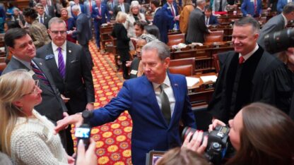 Brian Kemp is on the floor of the Georgia state House chamber surrounded by lawmakers