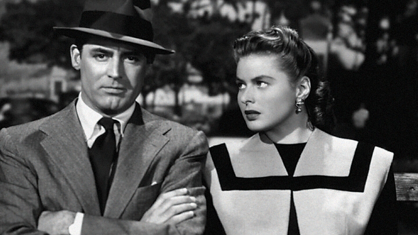 Black-and-white still from Notorious showing Cary Grant and Ingrid Bergman seated closely, exchanging a guarded look.