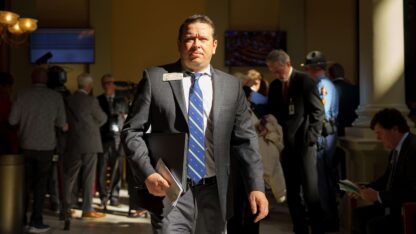 A man in a suit walks down a hallway in the Georgia State Capitol