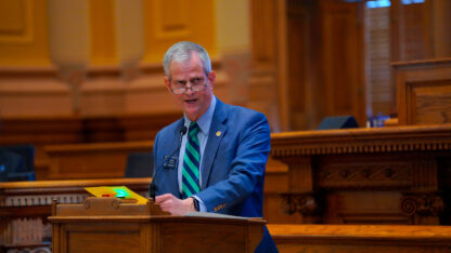 Ben Watson stands at a podium in the well of the Senate chamber at the Georgia State Capitol