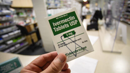 A person holds a box of ivermectin tables in a pharmacy