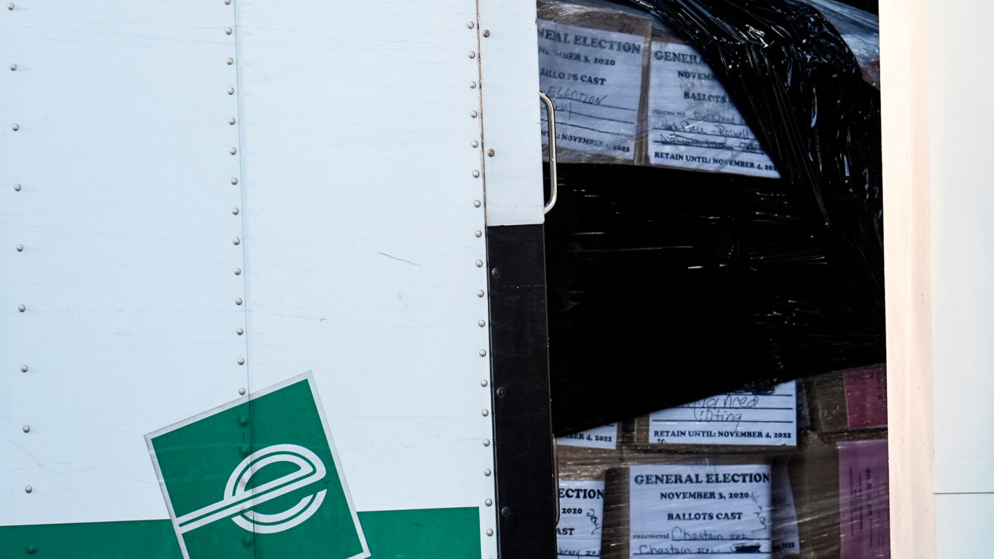 Boxes of voting ballots are shown loaded into a white and green moving truck